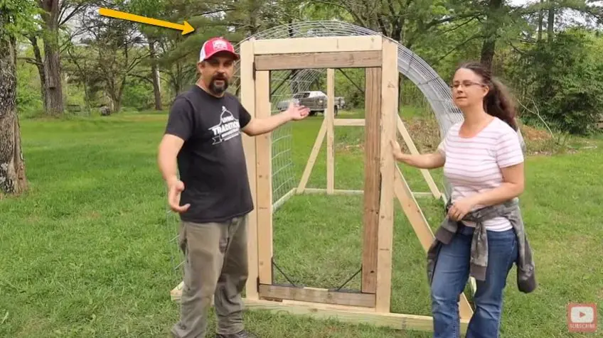Wooden door frame attached to a curved cattle-panel hoop coop